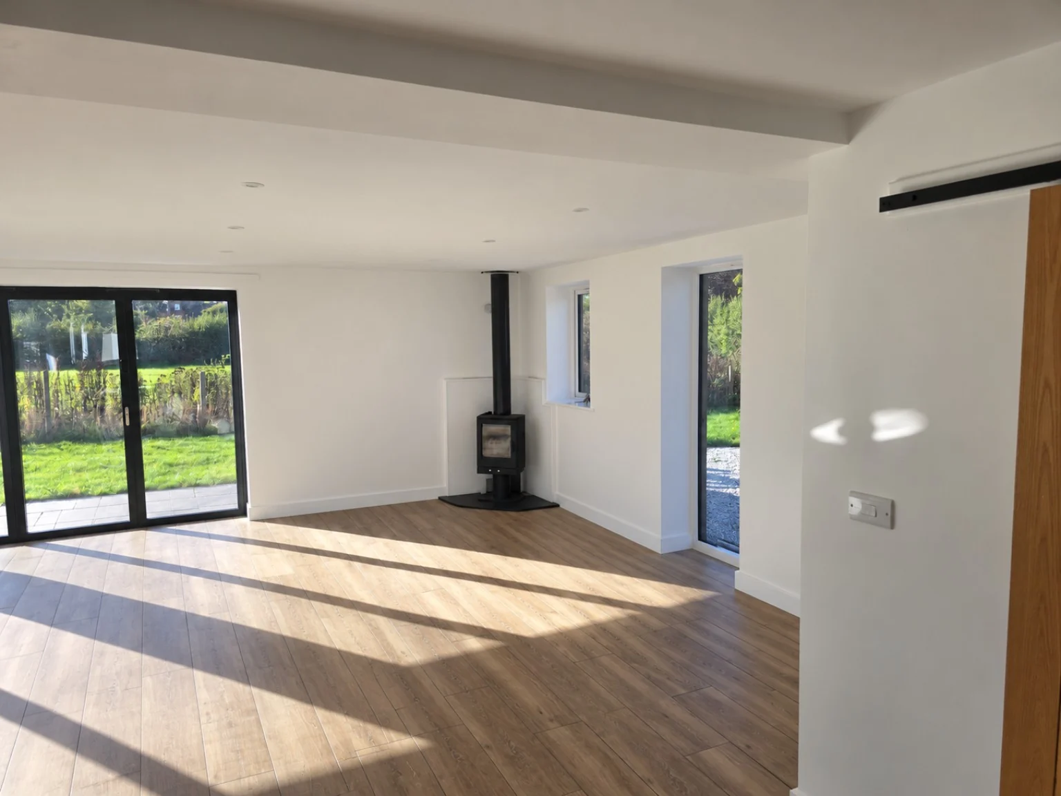 Interior finish example with white walls and ceiling, timber flooring and a wood-burning stove